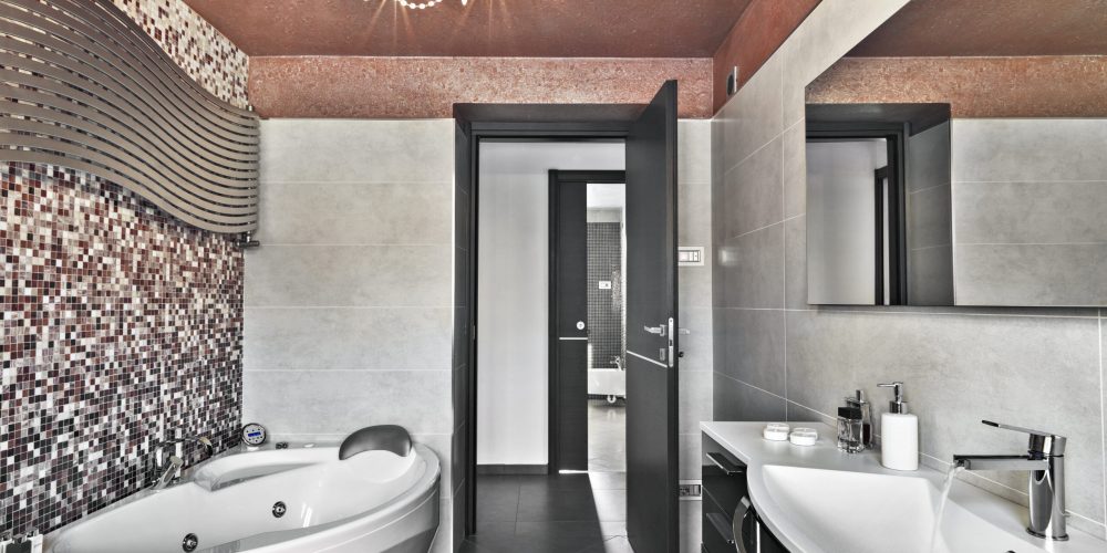 interiors of a modern bathroom to the left side the bathtub whie to the tight side the sink cabinet with inegrated washbasin above it there is a mirror