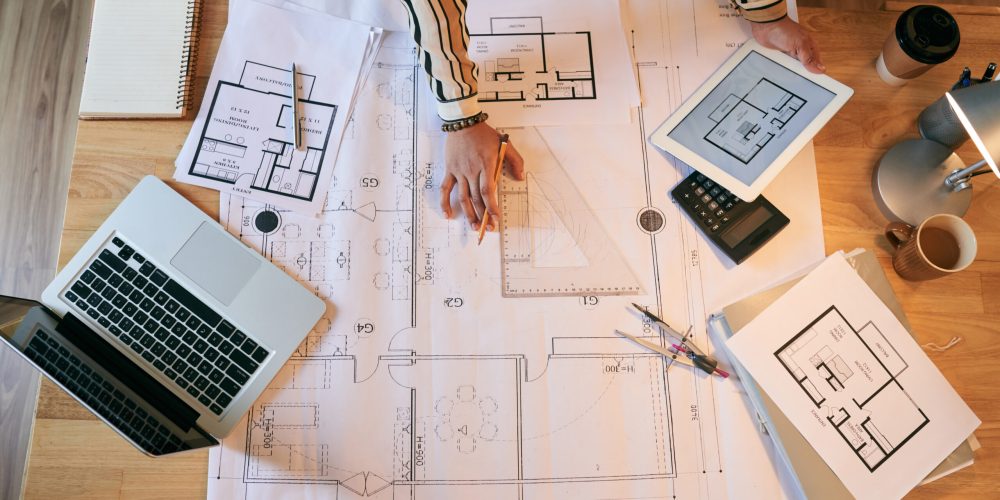 Female architect working on plan of the building, view from above
